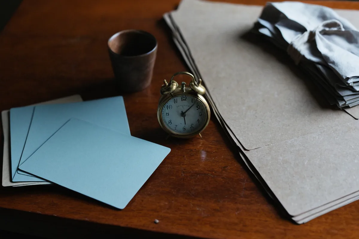 An analog clock, blank routine cards, shoes, and bags arranged before departure